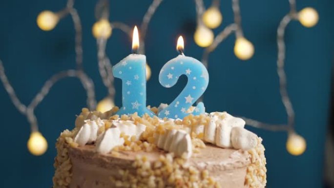 蓝色背景上有12个数字蜡烛的生日蛋糕。蜡烛吹灭了。慢动作和特写视图