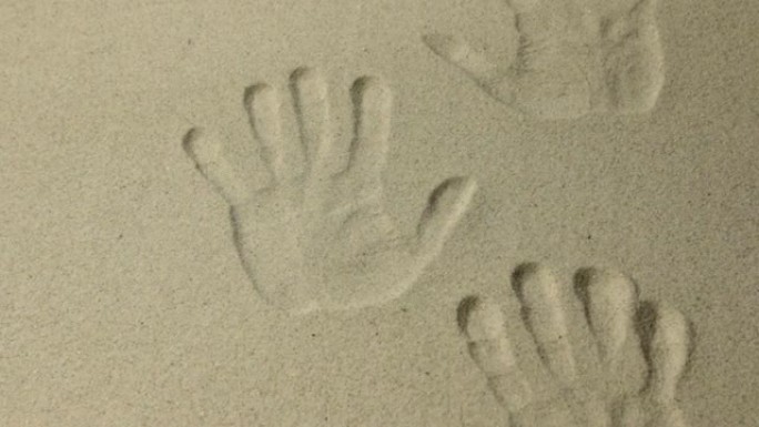 许多人类双手在沙滩上的印记，作为背景，缩放。