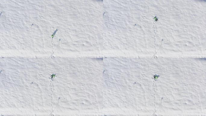 俯视男子走在冬季雪堆上。鸟瞰图男子在冬季散步时落在白色蓬松的雪上。快乐的人躺在冬天的雪地上。冬季人群