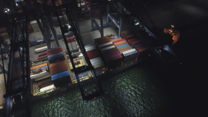 夜间工业港口的工作起重机和集装箱船