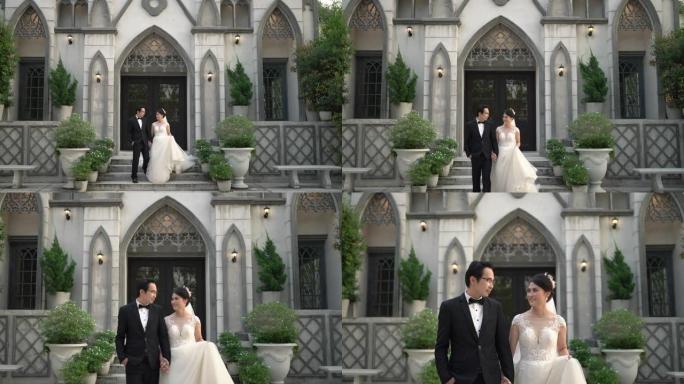 亚洲新娘和新郎一起牵着手走出教堂。恋爱中的新婚夫妇。手持镜头，真实生活