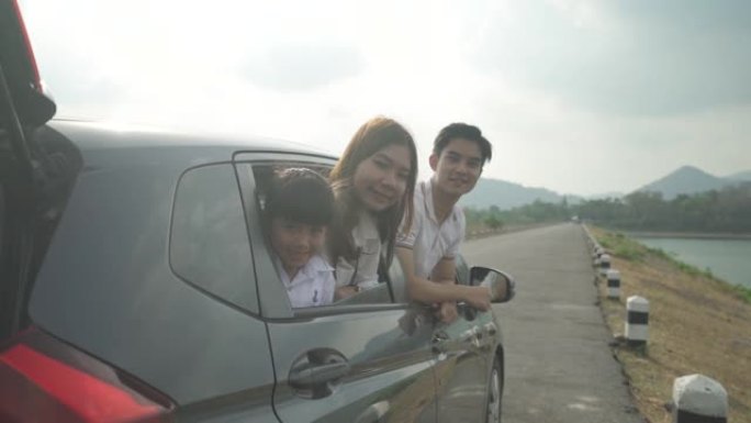 幸福的亚洲家庭，父亲，母亲和女儿在紧凑型汽车上微笑着开车去度假。汽车保险或租赁和家庭快乐的旅程概念。