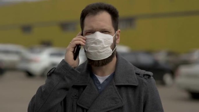 防止疾病和冠状病毒，一个戴着医用口罩的人在电话里说话