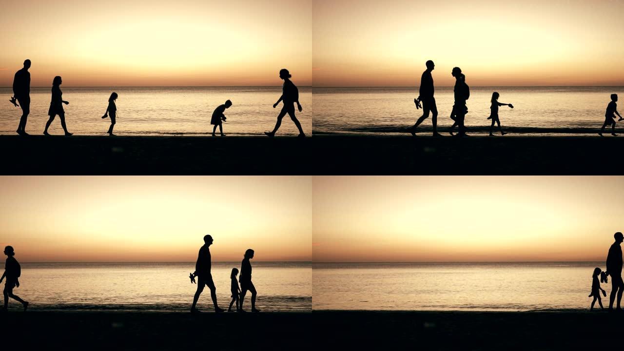 日落时在海滩散步的家庭剪影