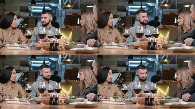 两对幸福的夫妇一起在餐厅享受友好的交谈，玩得开心。4k龙红相机
