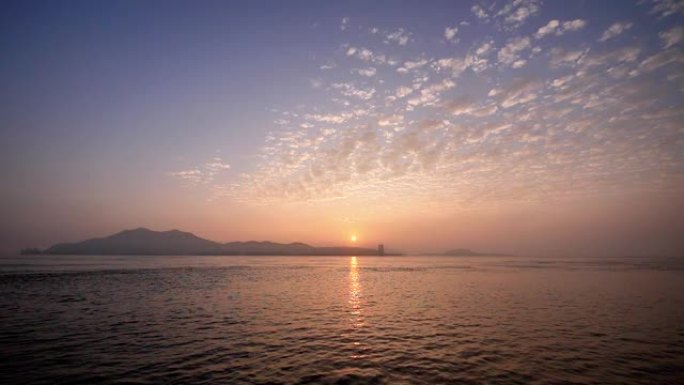 海上日出，轮廓岛和美丽的云彩背景，宁静的水面，微动的涟漪。
