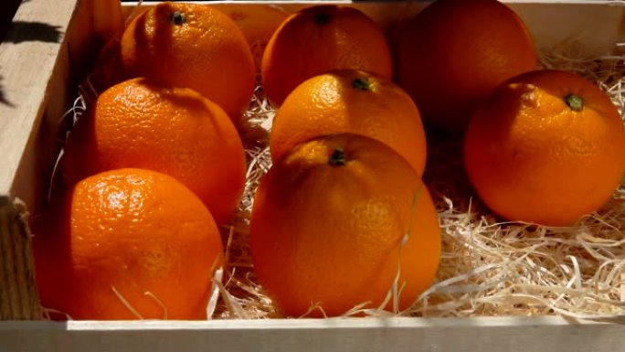 手将成熟多汁的橘子放在木箱中