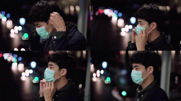 年轻的亚洲男子咳嗽与面罩保护在晚上