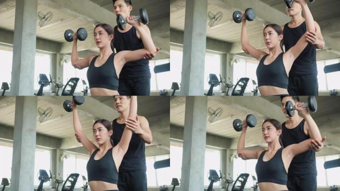 运动的男人和女人玩哑铃练习，进行手臂耐力训练，以增强和调理肩部肌肉。重量训练、运动和健康教育的概念。