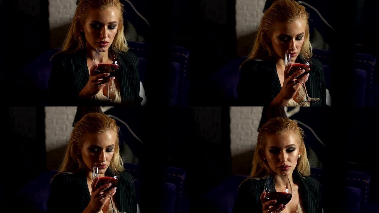 一个女孩晚上坐在酒吧里拿着一大杯红酒的特写镜头。
