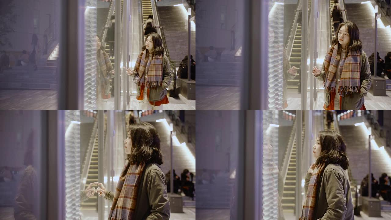 在一个寒冷的夜晚，亚洲女孩站在城市的商店橱窗外，她穿着保暖的衣服。