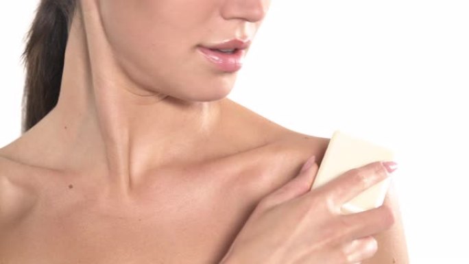 苗条的裸女正用一块肥皂轻轻地触摸她的前胸。护肤概念