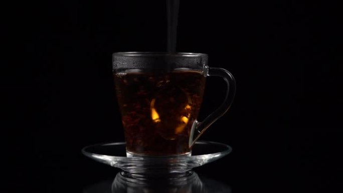 茶匙用茶杯和茶碟在黑色背景上搅拌热茶，慢动作。