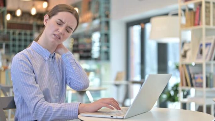 年轻的女商人在咖啡馆使用笔记本电脑时颈部疼痛
