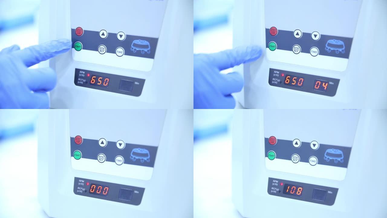 穿着白色实验室外套和蓝色乳胶手套的实验室技术员按下实验室测试设备上的开始按钮