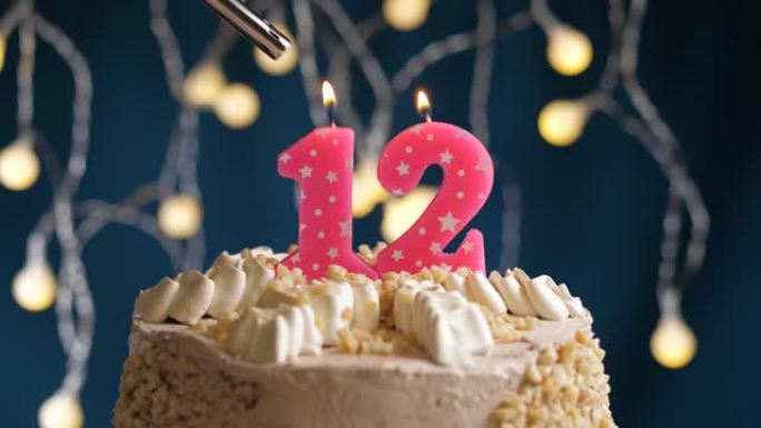 蓝色背景上有12号粉色蜡烛的生日蛋糕。蜡烛着火了。慢动作和特写视图