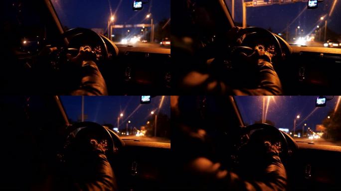 近距离的男性双手握住方向盘，并在夜间在高速公路上自动驾驶。司机开着他的越野车在路上行驶。年轻人晚上开