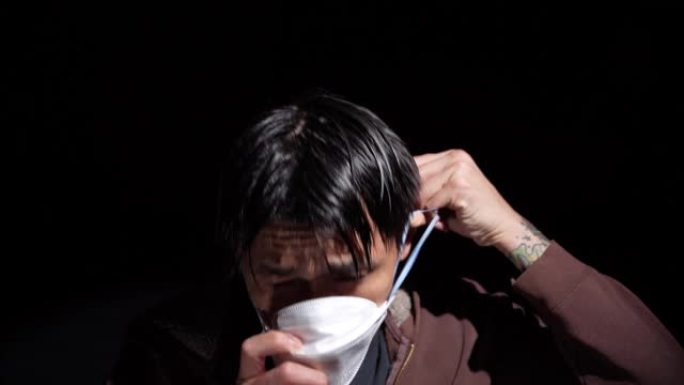 生病的亚洲男子咳嗽然后戴上医用口罩黑色背景