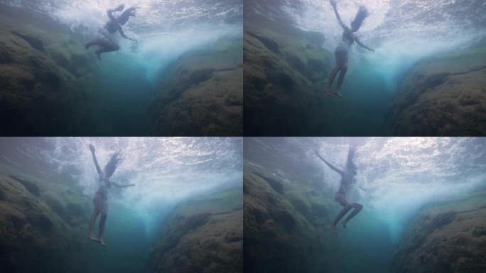 水下射击: 年轻的旅游女子以慢动作跳入瀑布。
