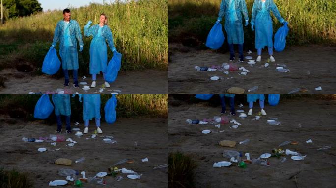 两名身穿蓝色长袍和手套的志愿者站在垃圾中的河岸上
