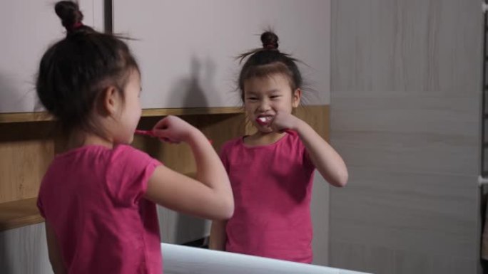 可爱的亚洲女孩在浴室镜子前刷牙