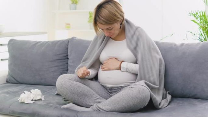 孕妇感冒，流感，病毒，坐在家里的沙发上，吹鼻子和生病。
