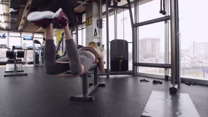 有吸引力的女运动员在健身房用阻力带做反向腿弯曲
