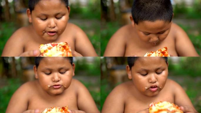 Asisn男孩在户外吃披萨