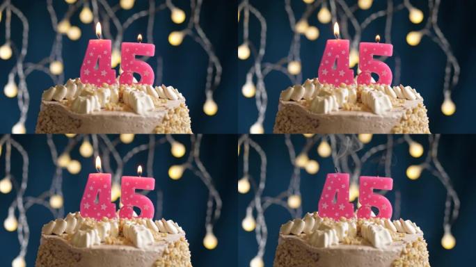 蓝色背景上有45号粉色蜡烛的生日蛋糕。蜡烛吹灭了。慢动作和特写视图