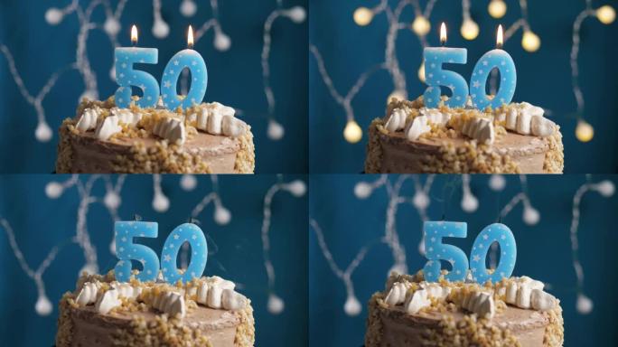 蓝色背景上有50号蜡烛的生日蛋糕。蜡烛吹灭了。慢动作和特写视图