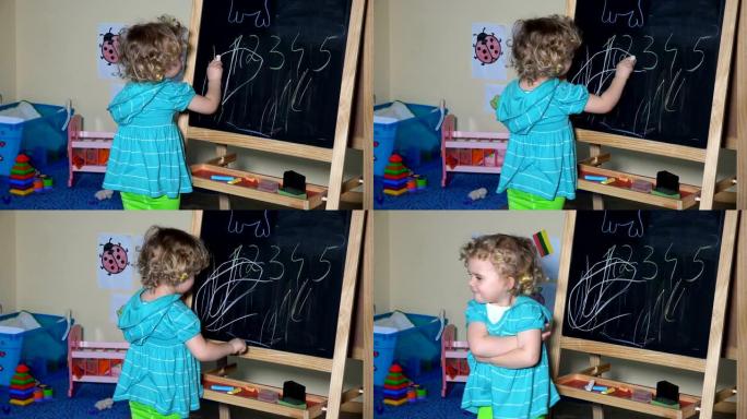 有趣的小孩可爱的金发学步女孩在黑板上用粉笔画画