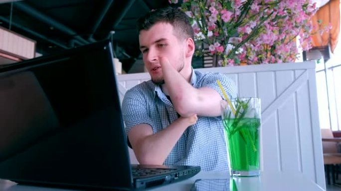 一个截肢的残疾人在咖啡馆用笔记本电脑视频聊天。