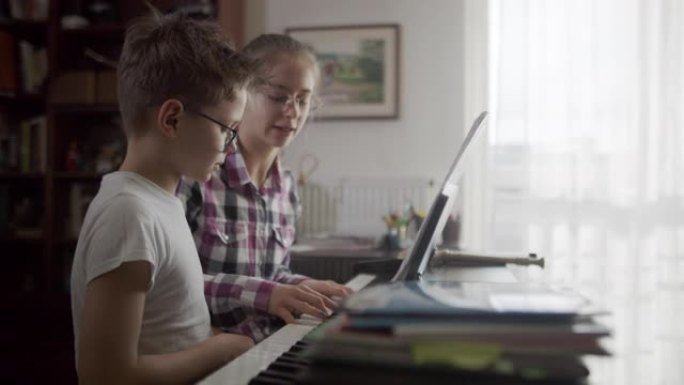 十几岁的女孩教她的兄弟弹钢琴