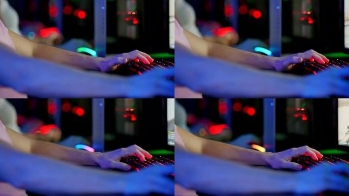 男人在电脑键盘上按手指，玩电脑游戏。电脑键盘在黑暗中发光。特写。
