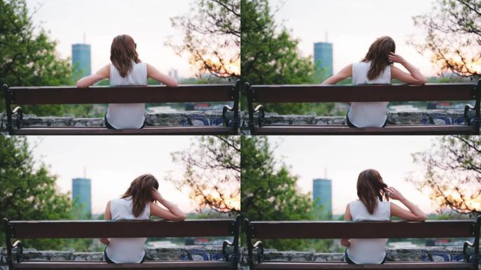 女人坐在长椅上，看着远处的城市风景。