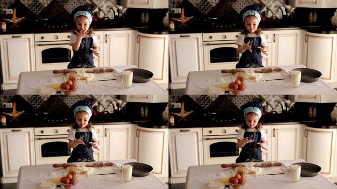 可爱的小女孩在厨房里用面团舔她的手指。