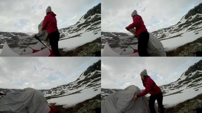 一名年轻女子在挪威特罗尔通加附近搭起帐篷。大自然中的野外露营。夫妻玩得很开心。他们被雪包围着。冬季登