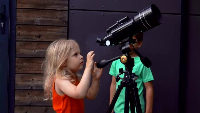 小女孩和一个可爱的男孩正在通过望远镜探索天空