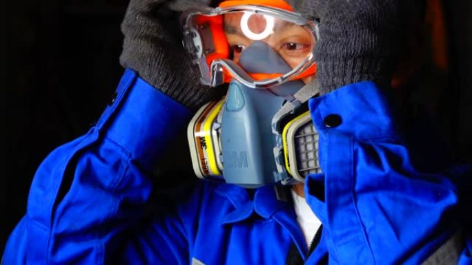 工程师戴防护眼镜和化学防护面罩与化学品罐一起工作。