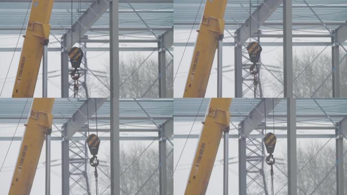 起重机和吊钩。钩一只黄色的起重机。建筑起重机吊臂，钢钩横跨施工现场。