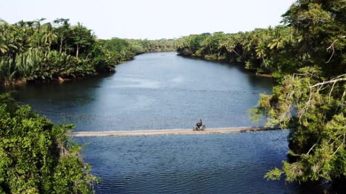 空中拍摄河上的吊桥，家伙与踏板车爪哇印度尼西亚一起驶过