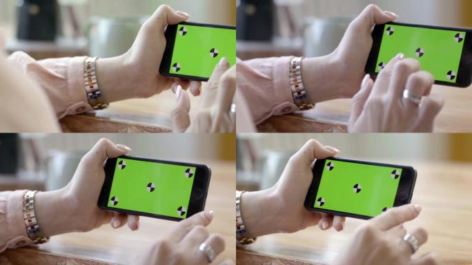女性双手拿着手机水平与绿屏特写。库存镜头。女性自由职业者在绿屏上点击电话