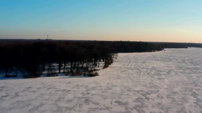 无人机在冬季景观，冰冻的湖泊和周围的森林中的景色