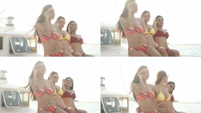 三个亚洲性感的女孩坐在游艇的前面或船头，看起来有趣和快乐的慢动作镜头。
