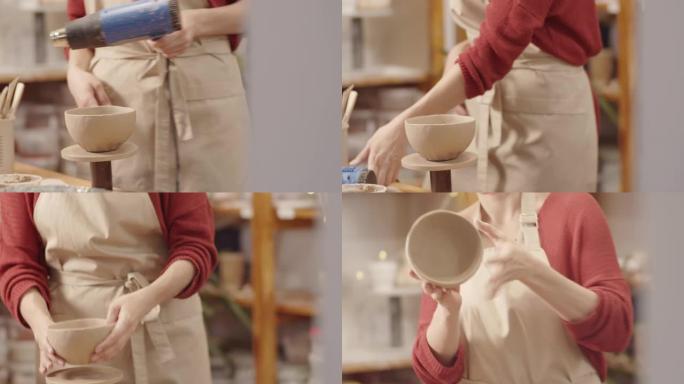 带热风枪和检查表面的女性陶工干燥粘土碗