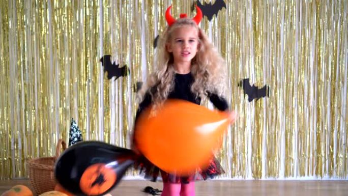 金色卷发的小恶魔女孩拿着气球在万圣节玩得开心