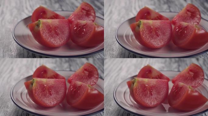 四片切成薄片的多汁番茄放在白色盘子上，木质纹理桌上有蓝色边框