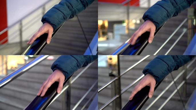 一名妇女用手指敲打下降的玻璃自动扶梯的栏杆。一个女人的手在购物中心的自动扶梯栏杆上的特写镜头。不露面