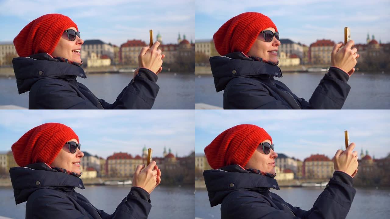 布拉格捷克戴着红帽子的年轻漂亮女人游客用智能手机微笑拍照