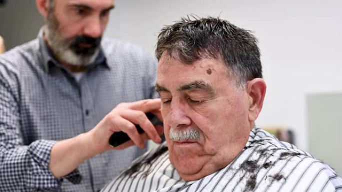 理发师在理发店修剪老人的头发。